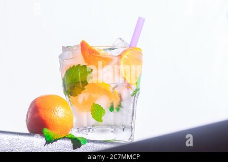 Mandarine Cocktail, Minze, Eis in einem rox Glas am Rand einer Theke weiß Hintergrund. Bot Ansicht, Nahaufnahme, horizontale Ausrichtung Stockfoto