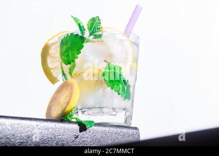 Cocktail Zitrone, Minze, Eis in einem rox Glas am Rand der Theke weiß Hintergrund. Bot Ansicht, Nahaufnahme, horizontale Ausrichtung Stockfoto