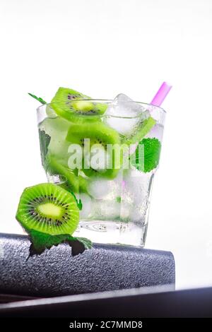 Kiwi Cocktail, Minze, Eis in einem rox Glas am Rand einer Theke weiß Hintergrund. Bot Ansicht, Nahaufnahme, vertikale Ausrichtung Stockfoto