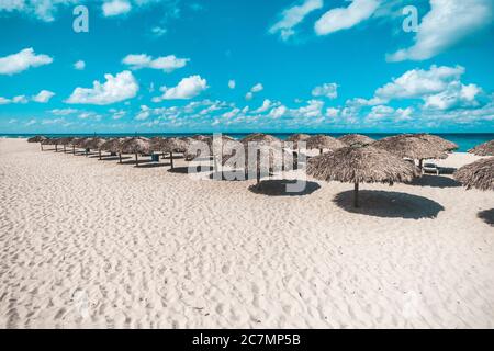 Viele reetgedeckte Sonnenschutze. Sonnenschirme stehen in einer Reihe auf Sand in einem Resort am Strand von Varadero in Kuba Stockfoto