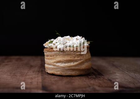 Tartlet mit Hüttenkäse und Kräutern auf Holzbrett und schwarzem Hintergrund Stockfoto