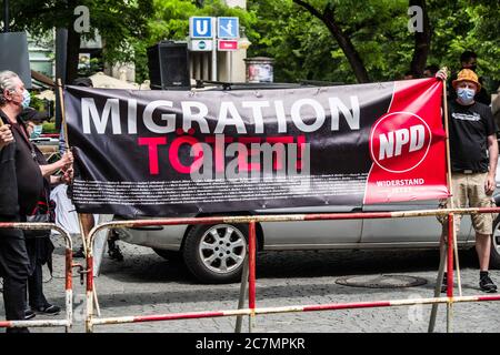 München, Bayern, Deutschland. Juli 2020. 'Migration tötet' auf Schildern der Neonazis NPD in München. Nach einer Pause, die zum Teil auf die Coronavirus-Krise und politische Verluste von Mitgliedern und Mitarbeitern wie Karl Richter zurückzuführen war, tauchten sechs von der neonazi NPD-Partei am Münchener Rotkreuzplatz mit bis zu 100 Gegendemonstranten gegen sie auf. Die Partei brachte während der Demonstration ihren Slogan "Migration Toetet" zurück und hat im August mehr versprochen. Unter anderem hatte die kleine Gruppe Verbindungen zu Mitgliedern der Terror Gruppe S. (Credit IMA Stockfoto