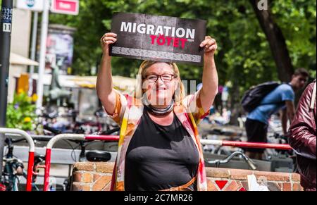 München, Bayern, Deutschland. Juli 2020. 'Migration tötet' auf Schilder von RENATE WERLBERGER von der neonazi NPD Partei in München. Nach einer Pause, die zum Teil auf die Coronavirus-Krise und politische Verluste von Mitgliedern und Mitarbeitern wie Karl Richter zurückzuführen war, tauchten sechs von der neonazi NPD-Partei am Münchener Rotkreuzplatz mit bis zu 100 Gegendemonstranten gegen sie auf. Die Partei brachte während der Demonstration ihren Slogan "Migration Toetet" zurück und hat im August mehr versprochen. Unter anderem hat die kleine Gruppe Verbindungen zu Mitgliedern des Terrors gehabt Stockfoto