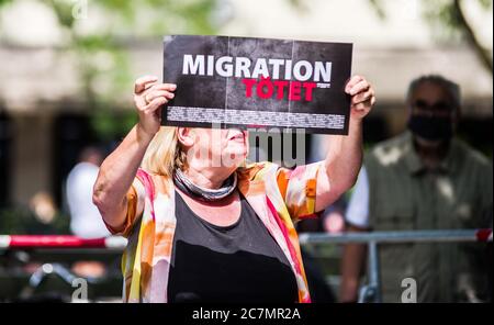 München, Bayern, Deutschland. Juli 2020. 'Migration tötet' auf Schilder von RENATE WERLBERGER von der neonazi NPD Partei in München. Nach einer Pause, die zum Teil auf die Coronavirus-Krise und politische Verluste von Mitgliedern und Mitarbeitern wie Karl Richter zurückzuführen war, tauchten sechs von der neonazi NPD-Partei am Münchener Rotkreuzplatz mit bis zu 100 Gegendemonstranten gegen sie auf. Die Partei brachte während der Demonstration ihren Slogan "Migration Toetet" zurück und hat im August mehr versprochen. Unter anderem hat die kleine Gruppe Verbindungen zu Mitgliedern des Terrors gehabt Stockfoto