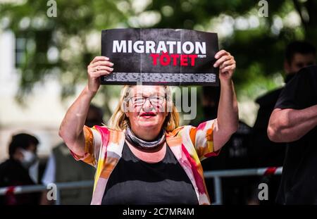 München, Bayern, Deutschland. Juli 2020. 'Migration tötet' auf Schilder von RENATE WERLBERGER von der neonazi NPD Partei in München. Nach einer Pause, die zum Teil auf die Coronavirus-Krise und politische Verluste von Mitgliedern und Mitarbeitern wie Karl Richter zurückzuführen war, tauchten sechs von der neonazi NPD-Partei am Münchener Rotkreuzplatz mit bis zu 100 Gegendemonstranten gegen sie auf. Die Partei brachte während der Demonstration ihren Slogan "Migration Toetet" zurück und hat im August mehr versprochen. Unter anderem hat die kleine Gruppe Verbindungen zu Mitgliedern des Terrors gehabt Stockfoto