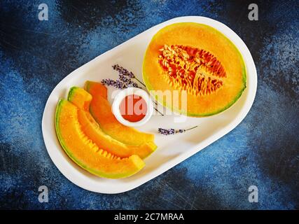 Süße Melone in Scheiben geschnitten mit Honig und Lavendel auf Eine weiße Platte Stockfoto