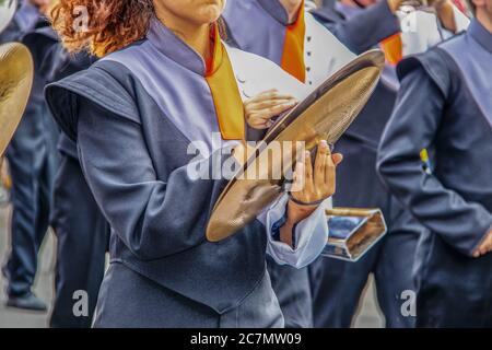 Mädchen in der High School marschieren Band spielen die Becken mit entschlossen aussehenden Kinn - nicht erkennbare Bandmitglieder und Bewegung verschwimmen auf den Händen Stockfoto