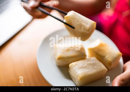 Gekochte Mochi-Reiskuchen geröstet im Ofen gebacken in traditioneller japanischer Weise auf dem Teller mit Hand halten Essen mit Essstäbchen Stockfoto