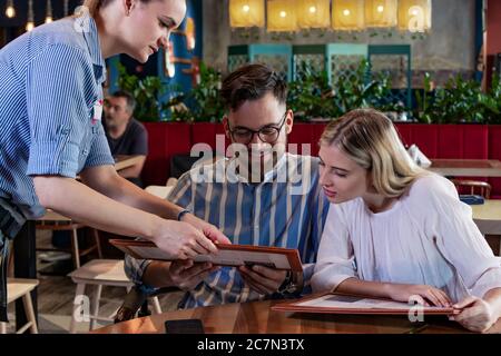 Happy Young romantisches Paar Bestellung, im Gespräch mit einer Kellnerin beim Abendessen in einem schönen schicken Restaurant. Stockfoto