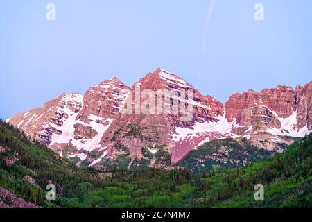 Maroon Bells Gipfel Nahaufnahme Blick in Aspen, Colorado zur blauen Stunde mit felsigen Bergen und Schnee im Juli 2019 Sommer bei Dämmerung mit lila rosa col Stockfoto