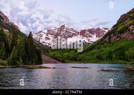 Kastanienbraune Glocken lila Farbe zur blauen Stunde in Aspen, Colorado mit Wolken im Morgengrauen vor Sonnenaufgang mit felsigen Berggipfel und See Reflexion im Sommer Stockfoto