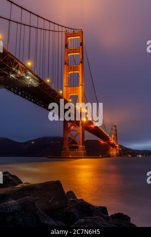 Die Golden Gate Bridge leuchtet und reflektiert den Sommer über Foggy Skies, via Fort Point. Stockfoto