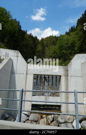 Betonbarriere eines Waldbaches, um zu verhindern, dass Steine ins Tal fallen mit starken Wasserstrahl aus schmelzendem Schnee in den Alpen. Stockfoto