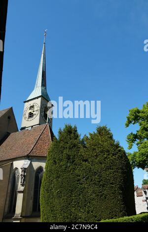 Zug / Schweiz 05 09 2020; St. Oswald-Kirchturm im gotischen Stil erbaut und von Vegetation umgeben auf dem Hintergrund des blauen Himmels. Stockfoto