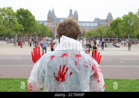 Menschen beobachten einen Aktivisten der Tieraufstand bei einer Protestaktion unter dem Motto Blut an den Händen am Museumplein inmitten des Coronavirus-Pandemi Stockfoto