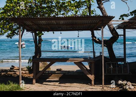 Ein Holztisch auf dem Sand vor einem Strand mit Blick auf das Karibische Meer in Puerto Viejo, Costa Rica Stockfoto