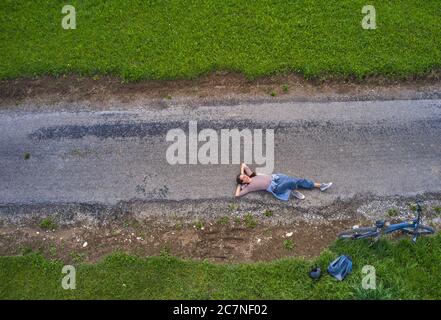 Marktoberdorf, 17. Juli 2020. Frau mit Mountainbike, entspannt in der Sonne auf einem Radweg liegen. © Peter Schatz / Alamy Stock Photos Stockfoto