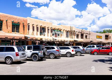 Taos, USA - 20. Juni 2019: Farbenfroher Plaza Platz in der Innenstadt in einem berühmten Stadtdorf mit Schild an der Außenfassade und Autos, die an sonnigen Tagen geparkt sind Stockfoto