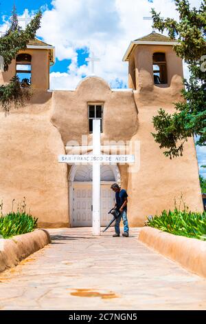 Ranchos de Taos, USA - 19. Juni 2019: St. Francic Plaza und San Francisco de Asis Kirche mit Kreuz und Mann Reinigung während der Bauarbeiten in New Mexico Stockfoto