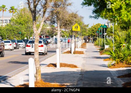 Seaside, USA - 25. April 2018: Bürgersteig und Schild in berühmten Stadt Stranddorf während sonnigen Tag in Florida Panhandle Golfküste mit Autos in Traff Stockfoto