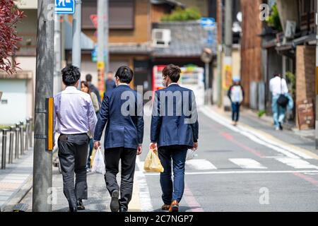 Kyoto, Japan - 17. April 2019: Gruppe von Menschen Geschäft Salaryman zu Fuß in Anzug zurück für das Mittagessen Holding Laden gekauft Lebensmittel in Plastiktüten auf der Straße r Stockfoto
