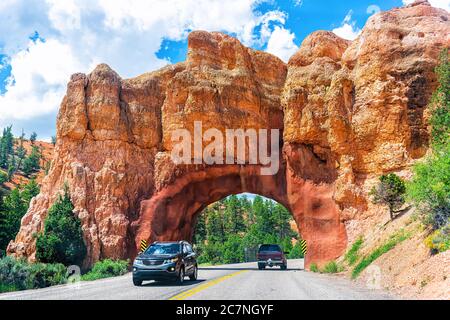 Bryce, USA - 2. August 2019: Autobahn in der Nähe des Bryce Canyon Nationalparks mit Loch Tunnel durch rot-orange Felsen in der Wüste mit Autos im Verkehr auf s Stockfoto