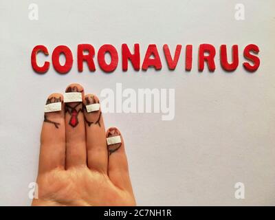 Gesichter mit Masken auf den Fingern und dem Wort Coronavirus gezeichnet Mit roten Buchstaben dahinter Stockfoto