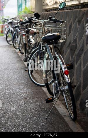 Fahrräder, die am Rande des Gehwegs in der Nähe des Bahnhofs in Japan geparkt sind. Stockfoto