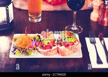 Bruschetta Lachs mit Avocado, Salatbeilage, Bier und Wein Stockfoto