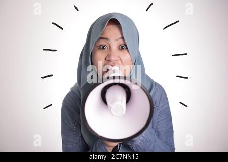 Junge asiatische muslimische Geschäftsfrau trägt Hijab schreiend mit wütenden Ausdruck auf Megaphon Stockfoto