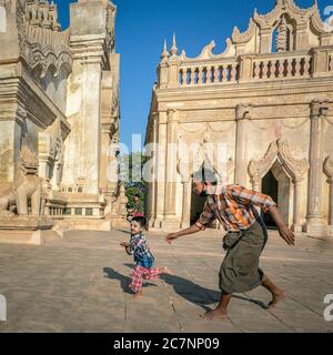 Ein Mann jagt seinem kleinen Sohn im Ananda Tempel in Bagan, Myanmar, nach Stockfoto