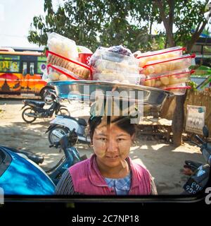 Eine burmesische Frau zeigt Snacks zum Verkauf auf einem Tablett auf dem Kopf in Mandalay, Myanmar Stockfoto