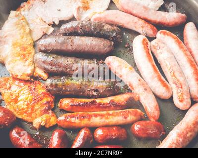 Overhead Schuss von verschiedenen Arten von Würstchen und Fleisch werden In einer schwarzen Pfanne gebraten Stockfoto