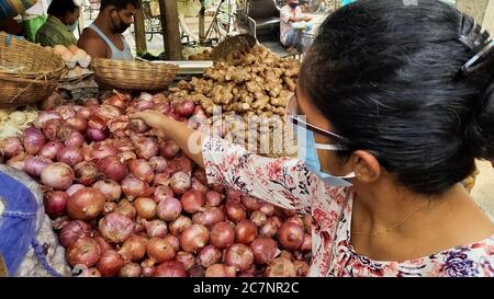 Lebensmittelgeschäft mit indischen Frau trägt schützende Gesichtsmaske Kauf Zwiebel auf einem lokalen Stadtmarkt in Kalkutta Indien Stockfoto