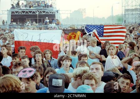 FILED - 21. Juli 1990, Berlin: Zuschauer stehen auf dem ehemaligen Todesstreifen am Potsdamer Platz und warten auf die Roger Waters Produktion des Pink Floyd Erfolges 'The Wall'. (Zu 'Rockspektakel auf Todesstreifen - 'die Mauer' vor 30 Jahren in Berlin') Foto: Wolfgang Kumm/dpa Stockfoto