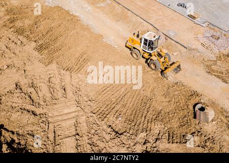 Gelber Radlader auf der Baustelle. Schwere Ausrüstung wird das Land graden. Top down Luftaufnahme Stockfoto