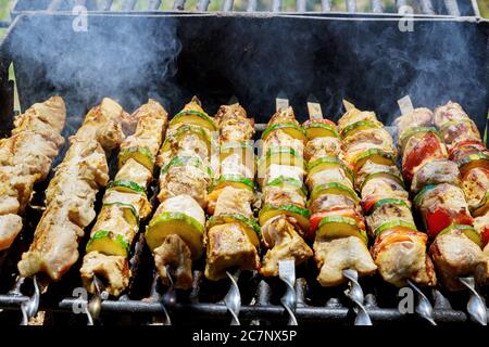 Spieße mit Schweinshaxe und Gemüse auf flammendem Grill. Stockfoto