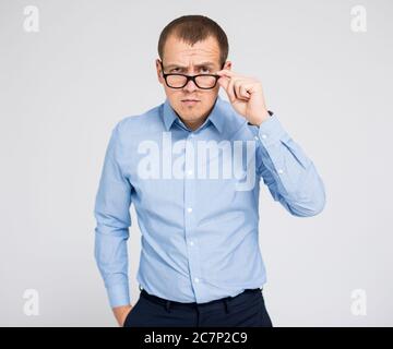 Porträt eines jungen ernsthaften Geschäftsmann in Brillen posiert über grauen Hintergrund Stockfoto