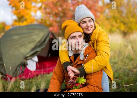 Reise, Liebe und Herbstkonzept - Portrait eines verliebten glücklichen Paares, das in der Nähe eines grünen Zeltes im Herbstwald posiert Stockfoto