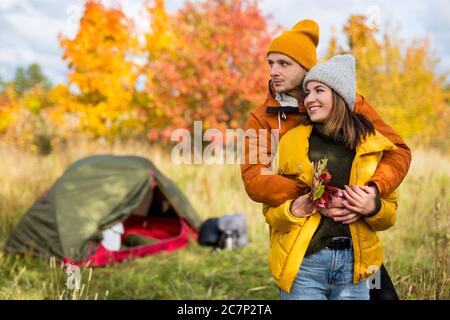 Reise, Liebe und Herbstkonzept - Portrait eines verliebten jungen Paares in der Nähe von grünem Zelt im Herbstwald Stockfoto