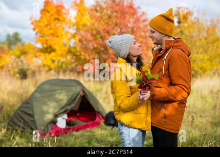 Reisen, Trekking, Wandern und Liebeskonzept - Portrait eines verliebten Paares posiert in der Nähe von grünem Zelt im Herbstwald Stockfoto