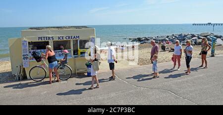 FELIXSTOWE, SUFFOLK, ENGLAND - 26. JUNI 2020 : gesellschaftlich distanzierte Schlange für Eis am Meer Promenade Strand und Meer im Hintergrund. Stockfoto