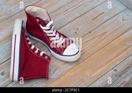 High Angle Ansicht von roten High Top Sneakers auf einem Holzboden unter den Lichtern Stockfoto