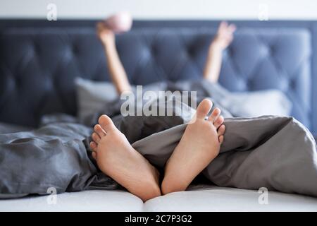 Good Morning Konzept - weibliche Hände und Beine ragen aus der Decke im Schlafzimmer Stockfoto