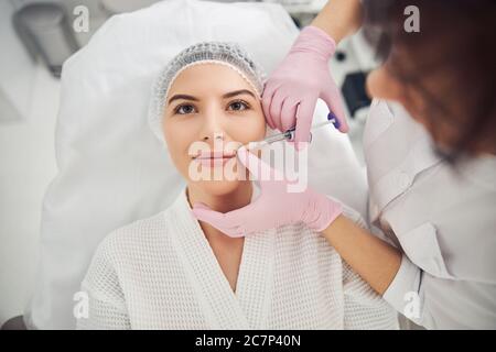 Optimistische Patientin mit injizierbarer Schönheitsbehandlung Stockfoto