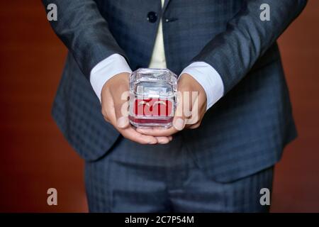 Nahaufnahme von zwei goldenen Ringen in männlichen Händen gehalten- Heiratskonzept Stockfoto