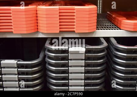 Nahaufnahme von schwarzen Kunststoffbehältern und rot gestapelten Deckeln Auf Regalen in einem Baumarkt Stockfoto