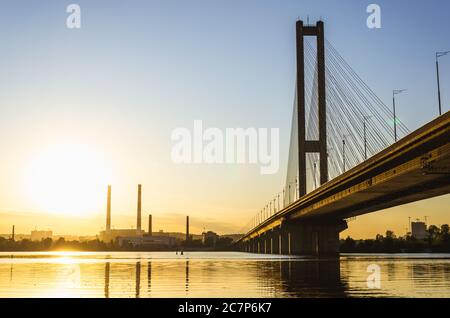 Südbrücke, Kiew, Ukraine. Kyiv Brücke über den Fluss Dnipro vor der Kulisse eines schönen Sonnenuntergangs. Die Brücke in der Abendsonne Stockfoto