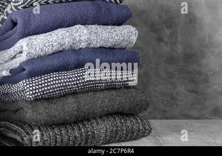 Stapel von gefalteten warmen Strickpullover für Herren auf grauem Hintergrund. Speicherplatz kopieren. Nahaufnahme Stockfoto