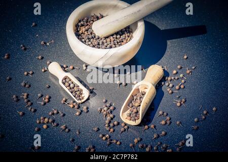 Pfefferkörner aus Pfeiferkubeba mit einem Holzlöffel Stockfoto